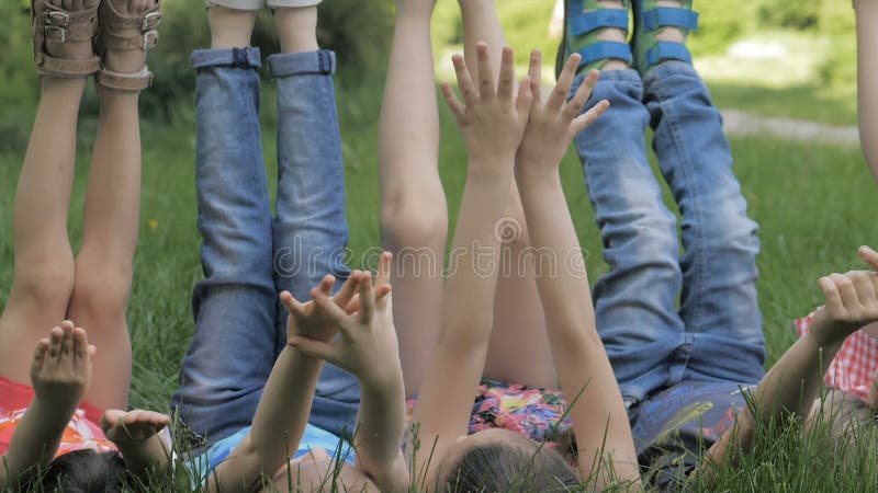 Groupe d'enfants heureux allongés sur l'herbe verte en plein air dans le parc de printemps clips vidéos
