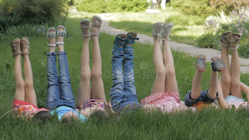 Groupe d'enfants heureux allongés sur l'herbe verte en plein air dans le parc de printemps clips vidéos