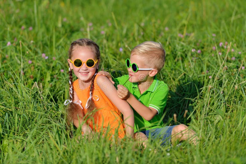 Groupe d'enfants heureux en verres de soleil ayant l'amusement dans l'herbe dehors images stock Groupe d'enfants heureux en verres de soleil ayant l'amusement dans l'herbe dehors images stock