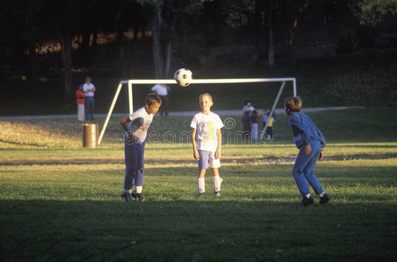 Groupe d'enfants jouant au football en stationnement photo libre de droits Groupe d'enfants jouant au football en stationnement photo libre de droits
