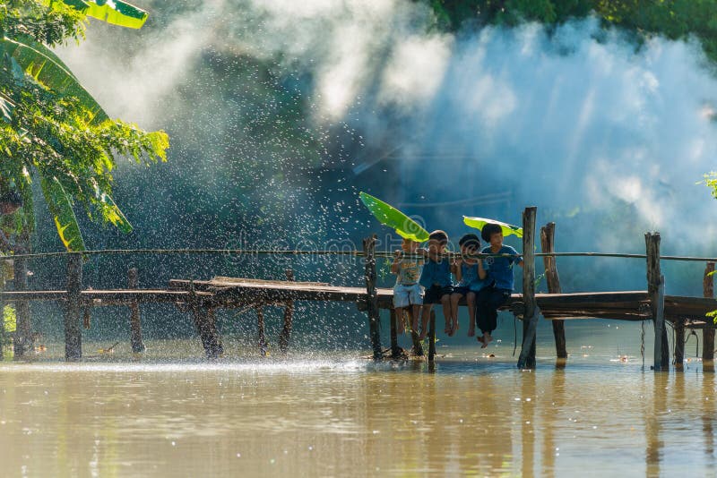 Groupe d'enfants ruraux s'asseyant ensemble sur le pont en bois photographie stock libre de droits Groupe d'enfants ruraux s'asseyant ensemble sur le pont en bois photographie stock libre de droits