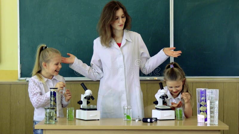 Groupe d'élèves avec la classe À l'aide de Science du professeur In Microscopes Une fois de plus à l'école et à l'enseignement à