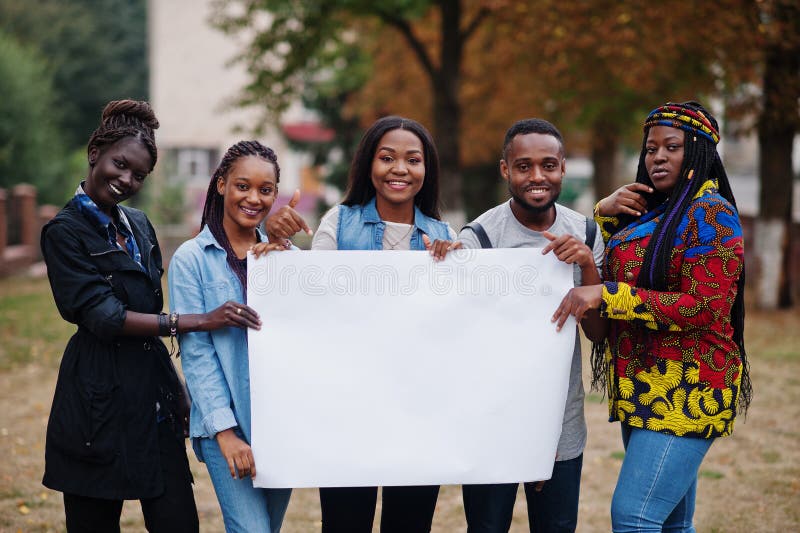 Group of five african college students on campus at university yard hold empty white blank. Free space for your text. Black afro friends studying. Group of five african college students on campus at university yard hold empty white blank. Free space for your text. Black afro friends studying