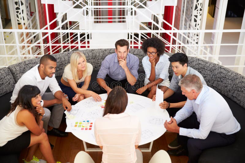 Groupe de collègues de travail ayant la réunion dans un lobby de bureau image stock