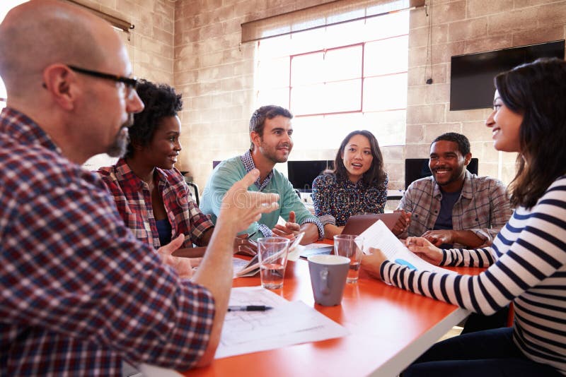 Group Of Designers Having Meeting Around Table In Office. Group Of Designers Having Meeting Around Table In Office