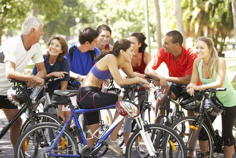Groupe de cyclistes se reposant pendant le tour de cycle par le parc images stock