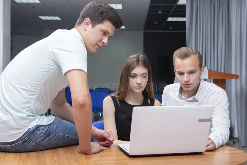 Groupe de deux jeunes étudiants euphoriques observant des résultats d'examen dans un ordinateur portable dans une table photographie stock libre de droits Groupe de deux jeunes étudiants euphoriques observant des résultats d'examen dans un ordinateur portable dans une table photographie stock libre de droits