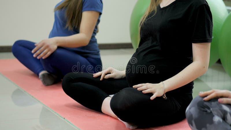 Groupe de femmes enceintes heureuses faisant de l'exercice de yoga et méditant dans la pose de lotus dans la salle de gym clips vidéos