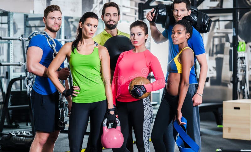 Groupe de femmes et d'hommes dans le gymnase posant à la formation de forme physique image stock Groupe de femmes et d'hommes dans le gymnase posant à la formation de forme physique image stock