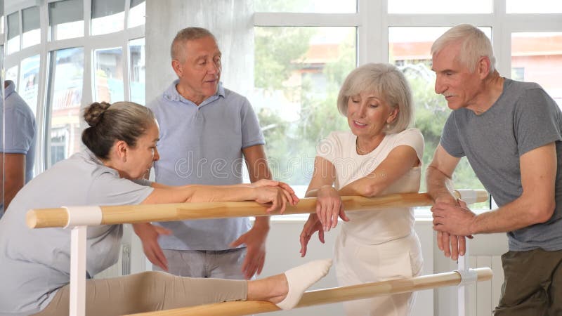 Groupe de femmes et d'hommes doués et joyeux détendus socialisant à la décontractée près du ballet barre après la pratique de la d clips vidéos