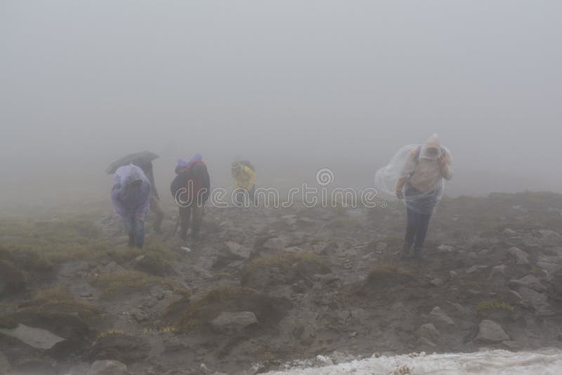 Groupe de grimpeurs dans des imperméables pendant le jour pluvieux et venteux photographie stock libre de droits Groupe de grimpeurs dans des imperméables pendant le jour pluvieux et venteux photographie stock libre de droits