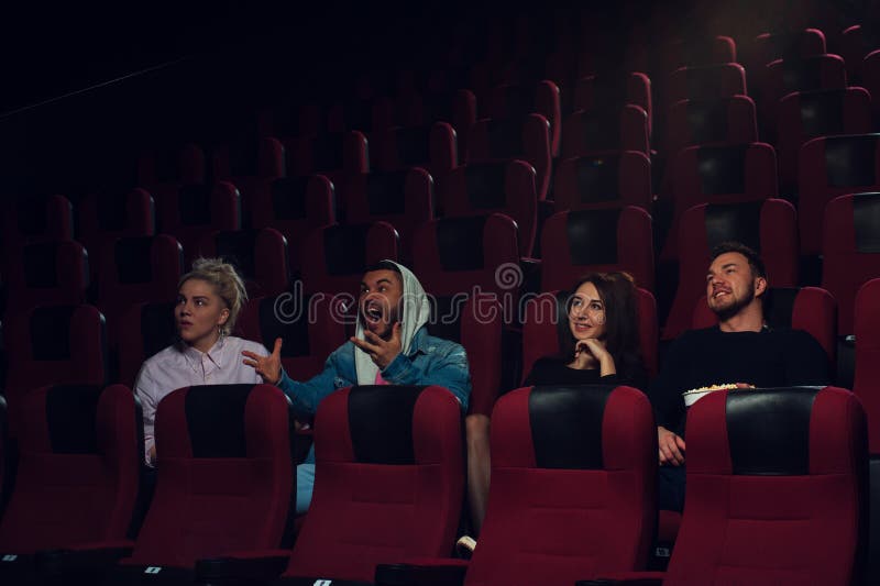Groupe de jeunes adultes observant le film dans le théâtre photographie stock libre de droits Groupe de jeunes adultes observant le film dans le théâtre photographie stock libre de droits