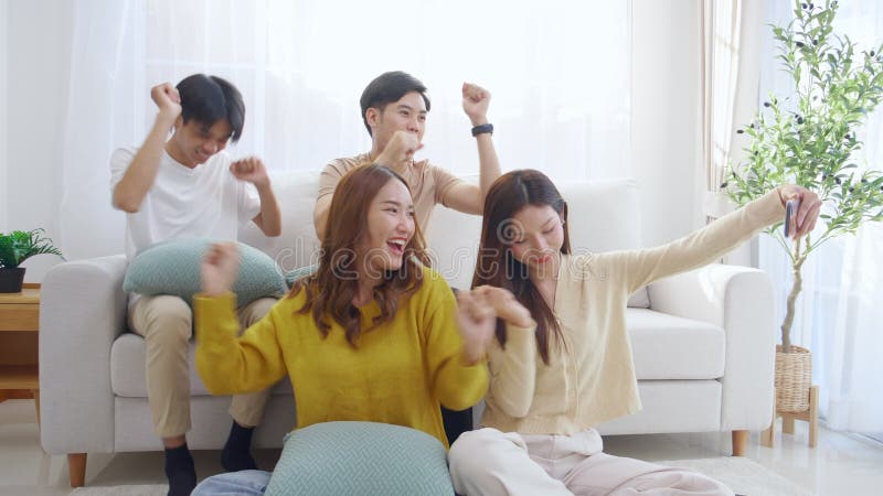 Groupe de jeunes amis asiatiques assis sur un canapé en prenant un selfie ou un appel vidéo en utilisant un téléphone intelligent clips vidéos