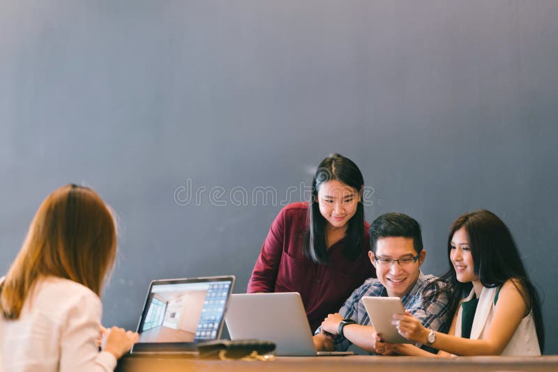 Groupe de jeunes collègues asiatiques d'affaires dans la discussion occasionnelle d'équipe, la réunion d'affaires de démarrage de image libre de droits
