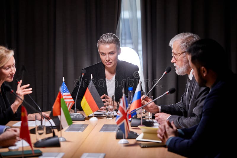 group of poltical leaders sitting with microphones at press conference, having talk, hold a meeting without ties to discuss ideas and issues on the agenda. in modern boardroom. group of poltical leaders sitting with microphones at press conference, having talk, hold a meeting without ties to discuss ideas and issues on the agenda. in modern boardroom