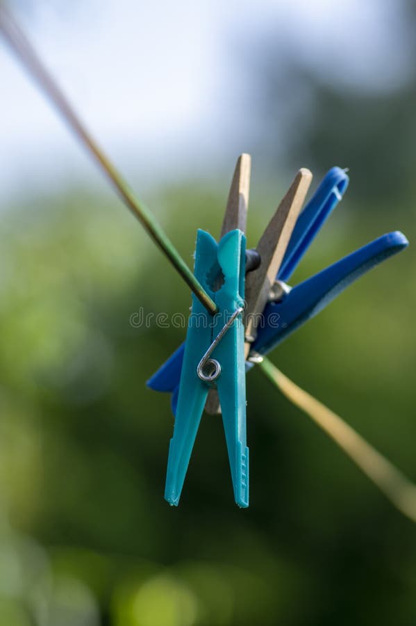 Groupe de peignoirs en plastique et en bois clair accrochés sur le fil à linge à la lumière du soleil, fond flou vert photos stock Groupe de peignoirs en plastique et en bois clair accrochés sur le fil à linge à la lumière du soleil, fond flou vert photos stock