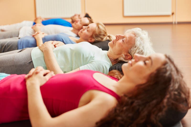 Groupe de personnes avec l'aîné faisant l'exercice de respiration. Groupe de personnes avec l'aîné détendant faisant l'exercice de respiration à la classe de yoga