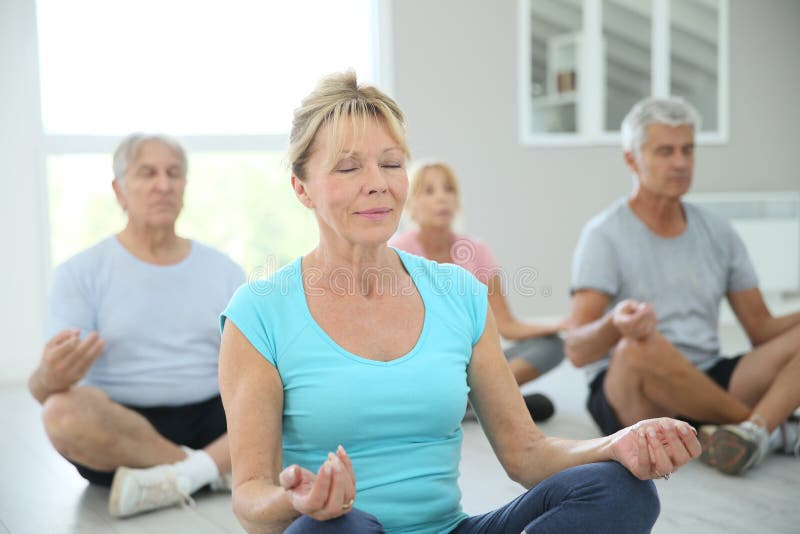 Groupe de personnes retraitées détendant faisant des excercises de yoga photo stock
