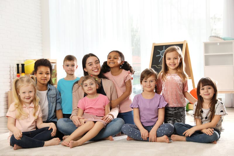 Groupe de petits enfants mignons avec le professeur s'asseyant sur le plancher images stock Groupe de petits enfants mignons avec le professeur s'asseyant sur le plancher images stock