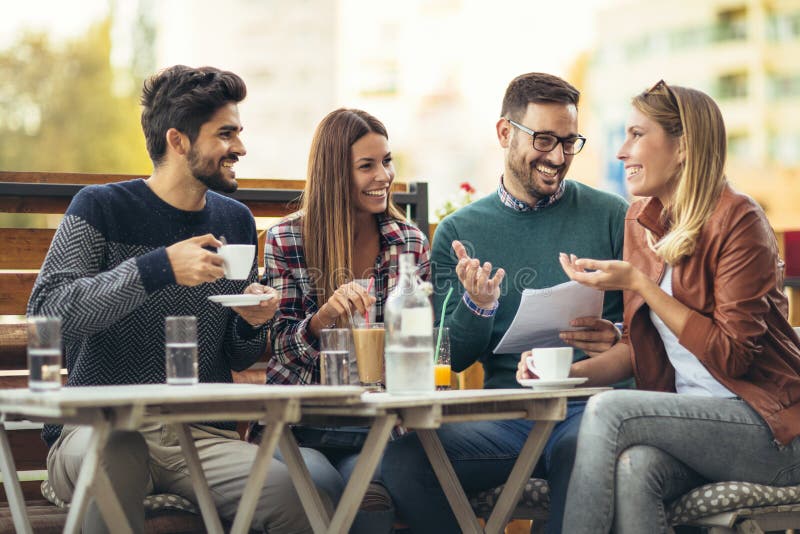 Group of four friends having fun a coffee together. Two women and two men at cafe talking laughing and enjoying their time. Group of four friends having fun a coffee together. Two women and two men at cafe talking laughing and enjoying their time