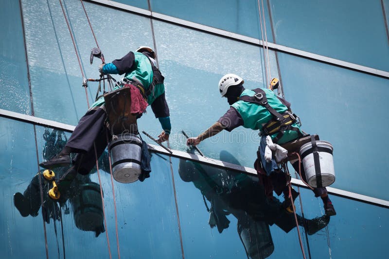Groupe de travailleurs nettoyant le service de fenêtres sur le bâtiment ayant beaucoup d'étages photographie stock libre de droits Groupe de travailleurs nettoyant le service de fenêtres sur le bâtiment ayant beaucoup d'étages photographie stock libre de droits