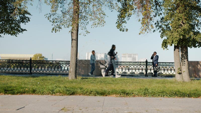 Groupe diversifié d'hommes et de femmes se déplaçant le long de la rue éclairée par le soleil le jour d'été banque de vidéos