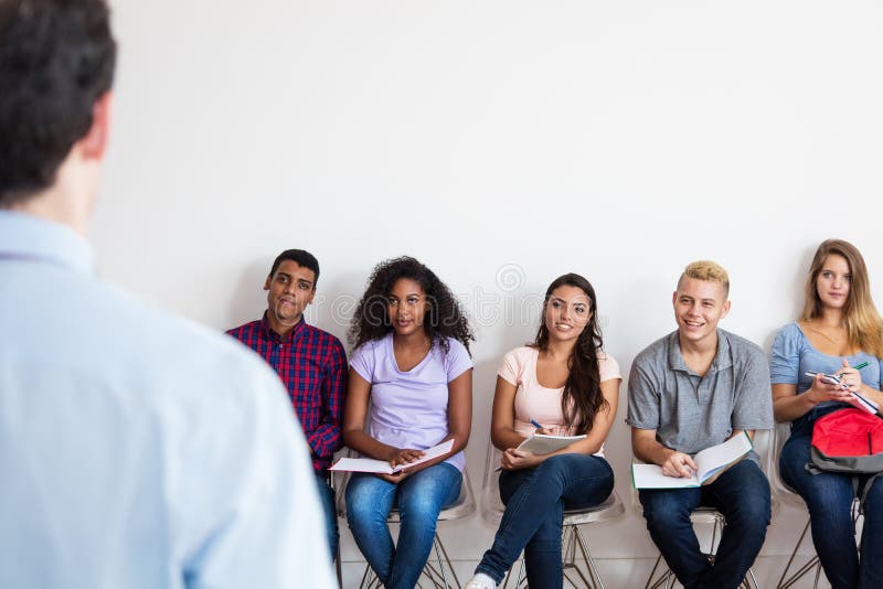 Groupe du jeune étudiant adulte écoutant le professeur photographie stock Groupe du jeune étudiant adulte écoutant le professeur photographie stock