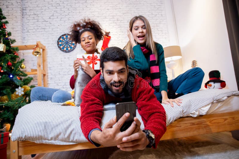 Groupe jeunes amis prendre selfie avec excité et profiter avec smartphone ensemble à la maison. photo stock