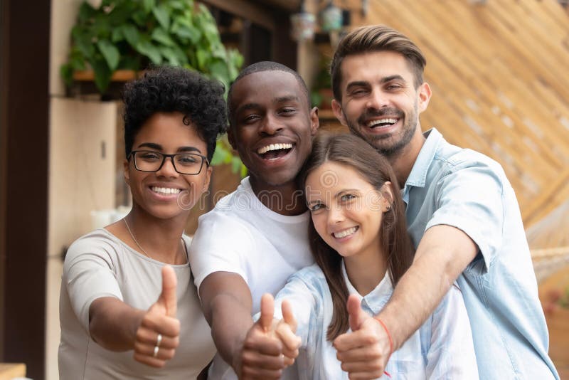 Groupe multi-ethnique heureux d'amis montrant des pouces vers le haut de regarder la caméra photo stock
