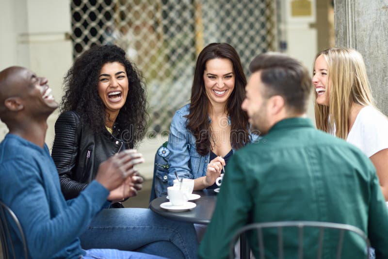 Multiracial group of five friends having a coffee together. Three women and two men at cafe, talking, laughing and enjoying their time. Lifestyle and friendship concepts with real people models. Multiracial group of five friends having a coffee together. Three women and two men at cafe, talking, laughing and enjoying their time. Lifestyle and friendship concepts with real people models