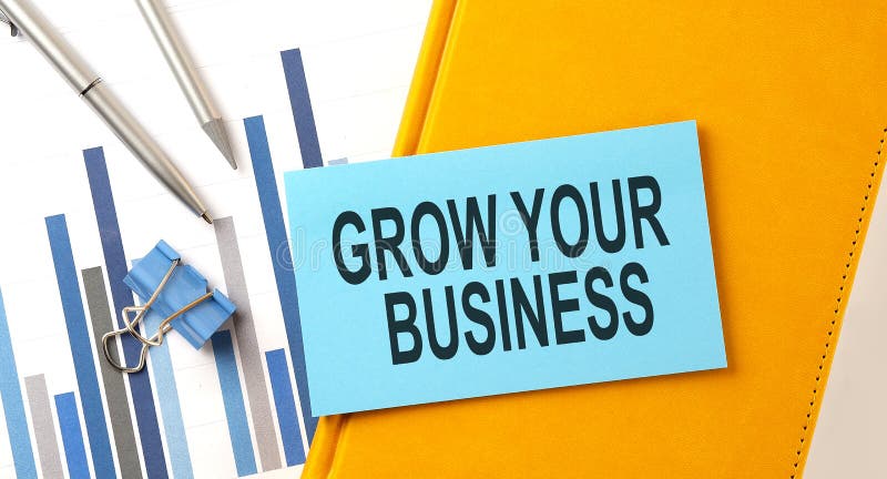 GROW YOUR BUSINESS text on sticker on yellow notebook with chart and pen royalty free stock images