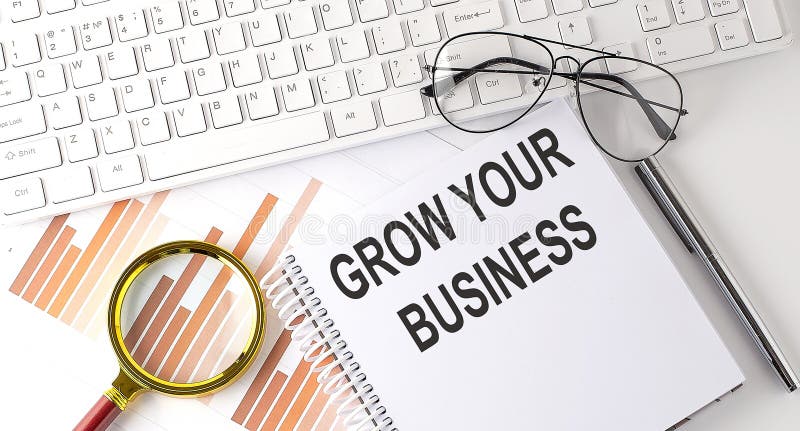 GROW YOUR BUSINESS text written on notebook with keyboard, chart,and glasses royalty free stock photos