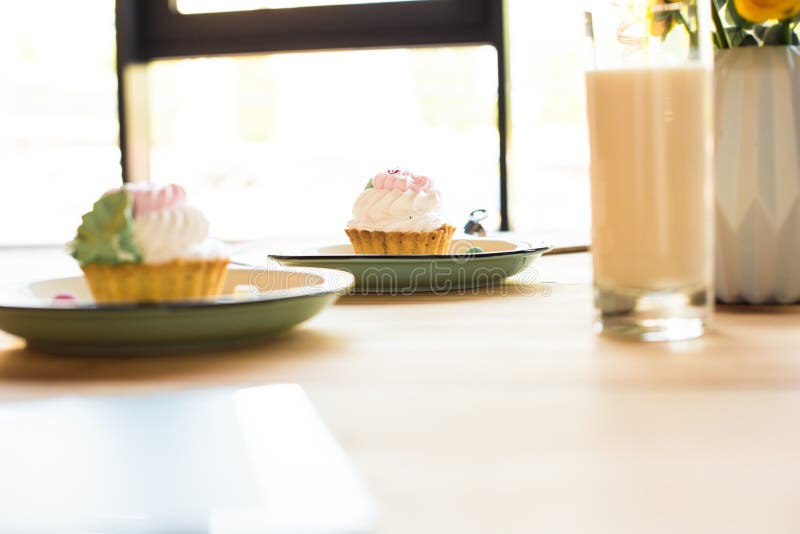 Großaufnahme des Milchshaken in den Glas- und köstlichen kleinen Kuchen auf Platten im Café stockfoto Großaufnahme des Milchshaken in den Glas- und köstlichen kleinen Kuchen auf Platten im Café stockfoto