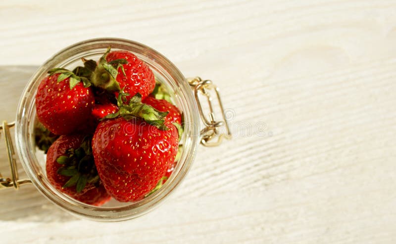 Große rote süße Erdbeere in einem Glasgefäß auf einem Holztisch lizenzfreies stockbild Große rote süße Erdbeere in einem Glasgefäß auf einem Holztisch lizenzfreies stockbild