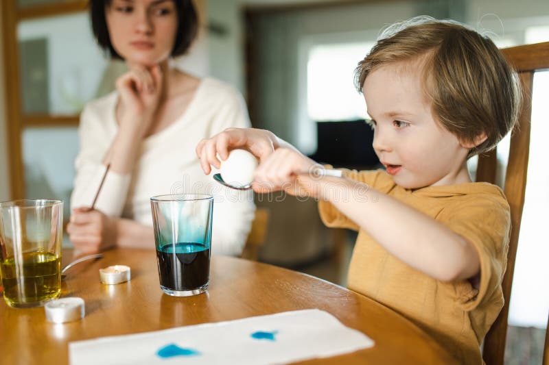Große Schwester und ihr kleiner Bruder färben Ostereier zu Hause. Kinder malen farbenfrohe Eier für die Osterjagd. Kinder bereiten sich auf Osterfeiern vor. Familientraditionen