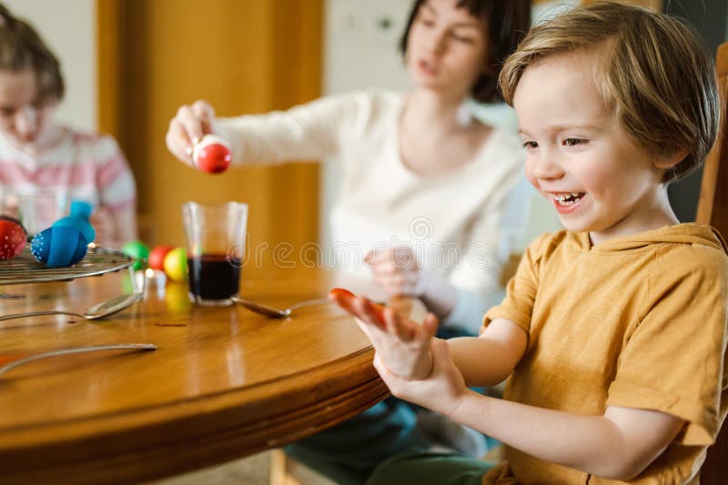 Große Schwester und ihr kleiner Bruder färben Ostereier zu Hause. Kinder malen farbenfrohe Eier für die Osterjagd. Kinder bereiten lizenzfreie stockbilder