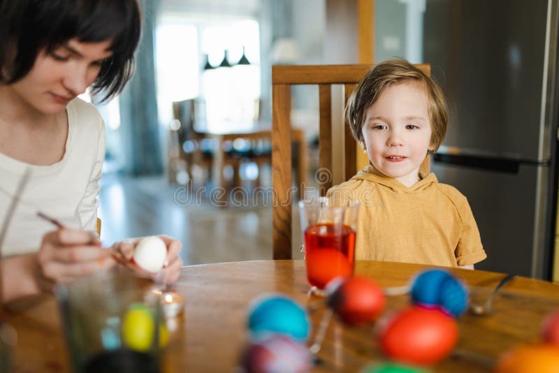 Große Schwester und ihr kleiner Bruder färben Ostereier zu Hause. Kinder malen farbenfrohe Eier für die Osterjagd. Kinder bereiten lizenzfreies stockbild
