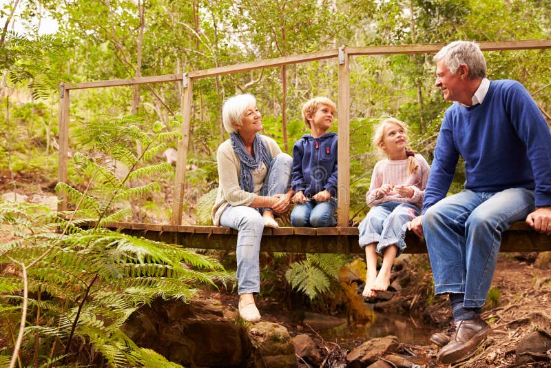 Großeltern, die mit Grandkids auf einer Brücke in einem Wald sitzen stockfoto Großeltern, die mit Grandkids auf einer Brücke in einem Wald sitzen stockfoto