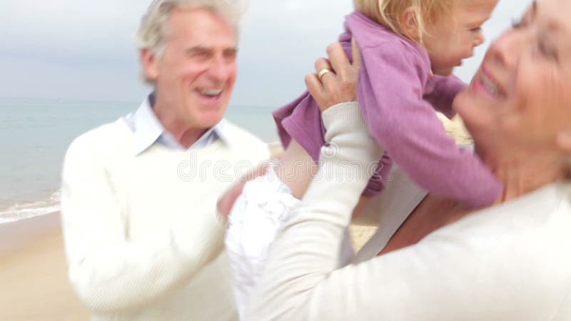 Großeltern und Enkelin, die zusammen entlang Strand gehen