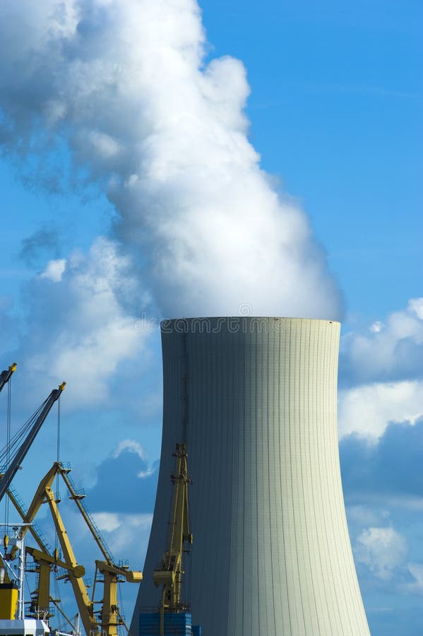 Large cooling tower at a large ship dock with cranes in foreground, cloudy blue sky behind the chimney. Large cooling tower at a large ship dock with cranes in foreground, cloudy blue sky behind the chimney