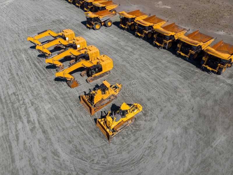 Large parking lot with big yellow mining truck, bulldozers for coal industry, ore and gold. Concept sale of industrial equipment. Aerial top view. Large parking lot with big yellow mining truck, bulldozers for coal industry, ore and gold. Concept sale of industrial equipment. Aerial top view.