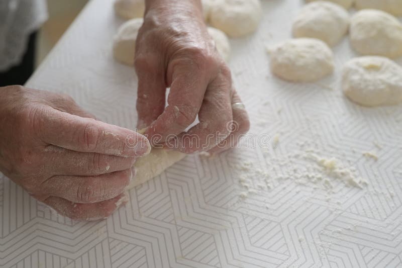 Grandmother`s hands close-up. Elderly woman cooks pies in the kitchen. Grandmother`s hands close-up. Elderly woman cooks pies in the kitchen