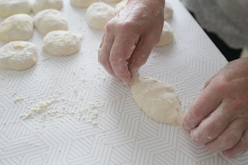 Grandmother`s hands close-up. An elderly woman cooks pies in the kitchen. homemade baking. Grandmother`s hands close-up. An elderly woman cooks pies in the kitchen. homemade baking