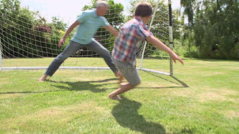 Großvater-, Enkel-und Vater-Playing Football In-Garten