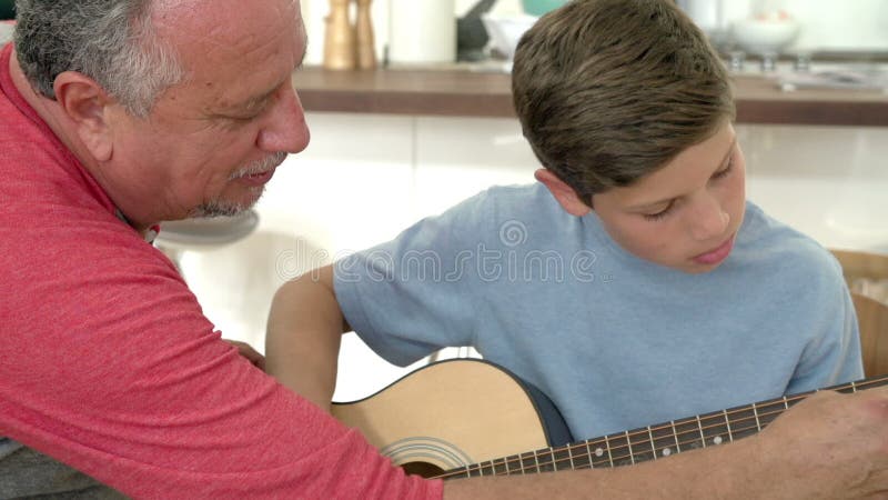Großväterlicher unterrichtender Enkel, zum der Gitarre zu spielen