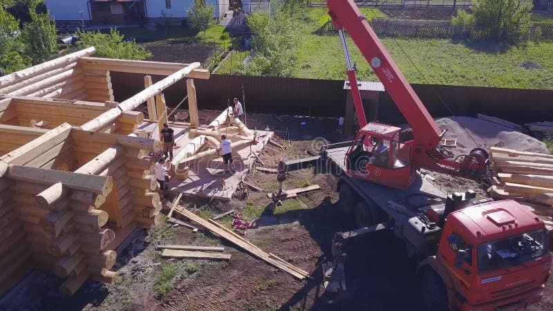 Grua e trabalhadores da construção de uma casa de madeira Clipe Visão superior do processo de trabalho com a equipe de trabalhado