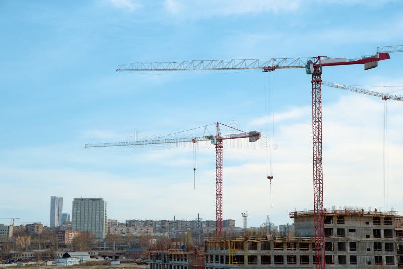 Grues de bâtiment et bâtiment en construction contre le ciel nuageux photo libre de droits Grues de bâtiment et bâtiment en construction contre le ciel nuageux photo libre de droits