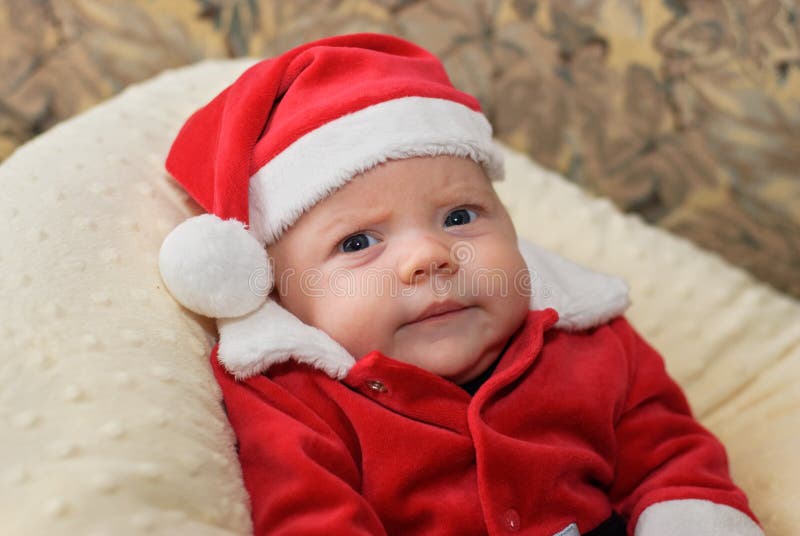 A close up portrait of a baby in a Santa suit with a grumpy expression. A close up portrait of a baby in a Santa suit with a grumpy expression.