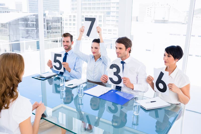 Grup de judecători ai comisiei care dețin semne de punctaj în fața unei femei stock photography