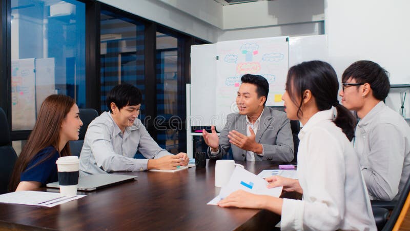 Grupa azjatyckich biznesmenów dyskutuje razem w zespole spotkanie burzy mózgów praca późno w nocy w biurze
